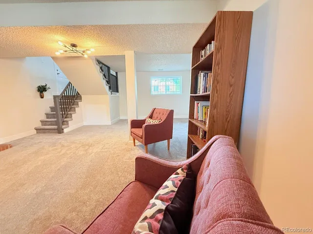 a furnished livingroom with a large window and a chair