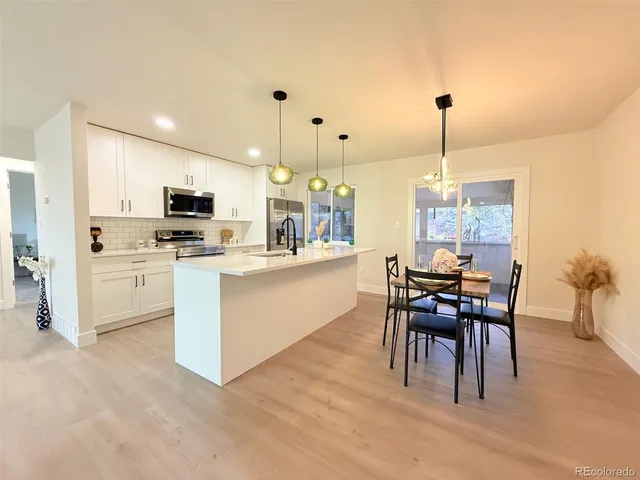 a kitchen with kitchen island a dining table chairs stainless steel appliances and cabinets