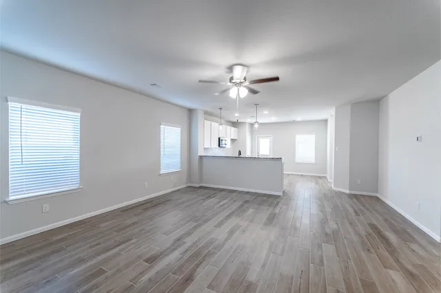 a view of an empty room with a window and wooden floor