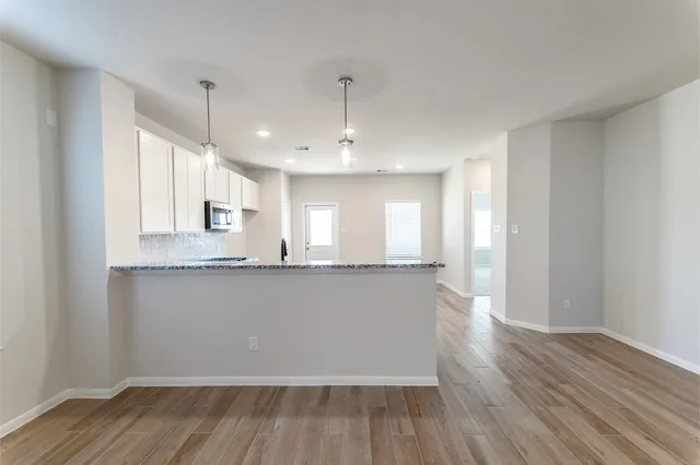 a large kitchen with hardwood floor sink granite counter tops and a window