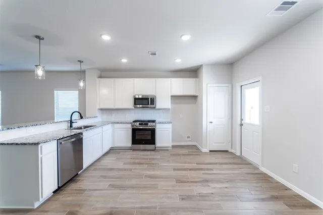 a large kitchen with stainless steel appliances kitchen island a large counter top and a stove top oven
