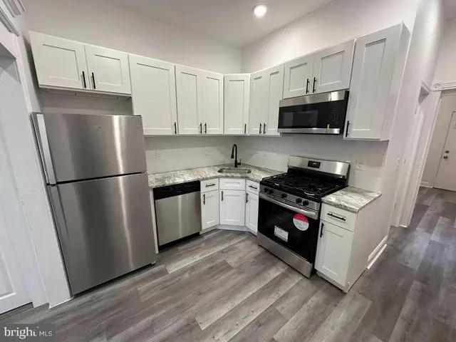 a kitchen with stainless steel appliances a refrigerator stove and white cabinets