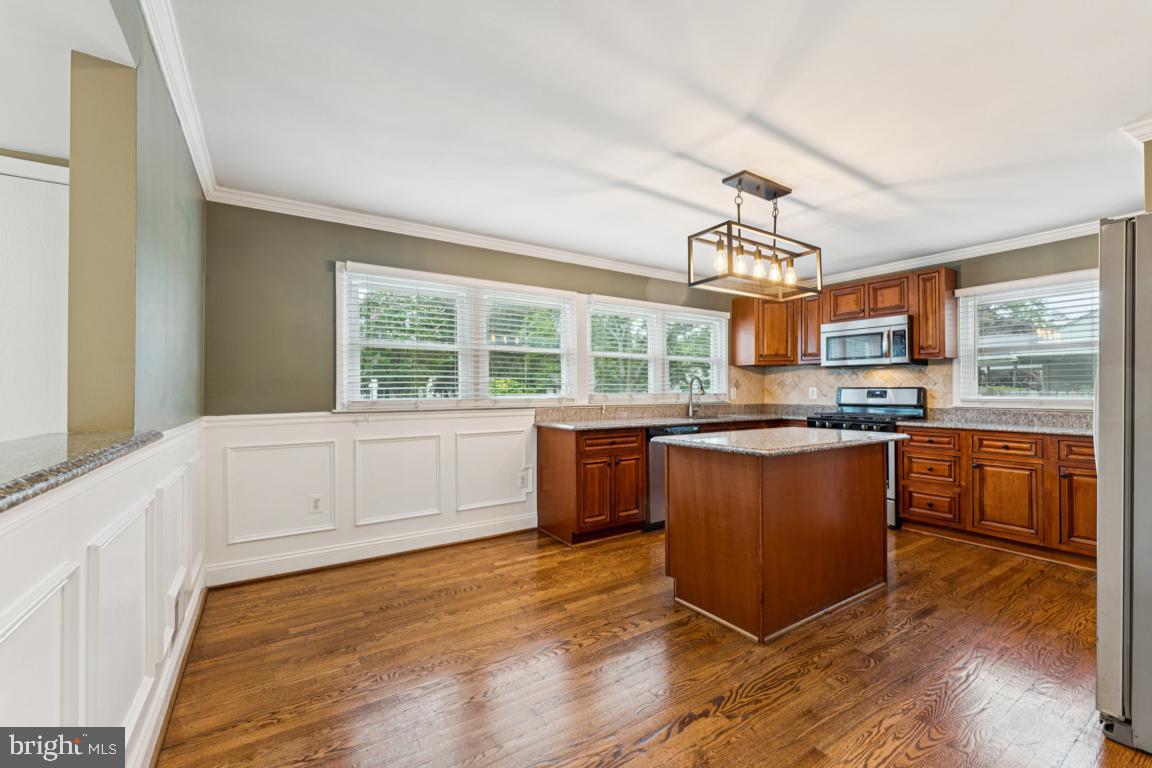 5 Brookfield Road Pasadena, MD 21122 - Photo 5 of 34 a kitchen with stainless steel appliances granite countertop a stove a sink dishwasher and white cabinets with wooden floor