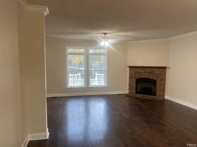an empty room with wooden floor and windows with curtains