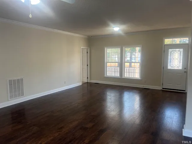 a view of an empty room with wooden floor and fireplace