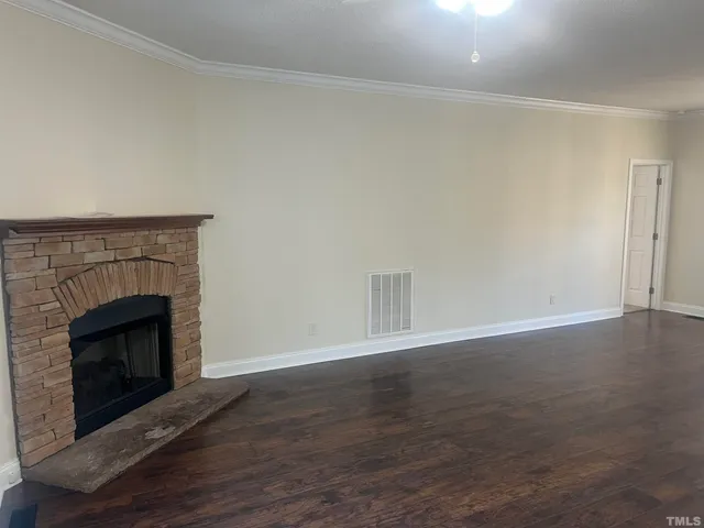 an empty room with wooden floor fireplace and windows