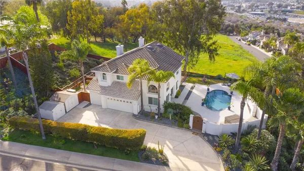 an aerial view of a house with swimming pool and large trees