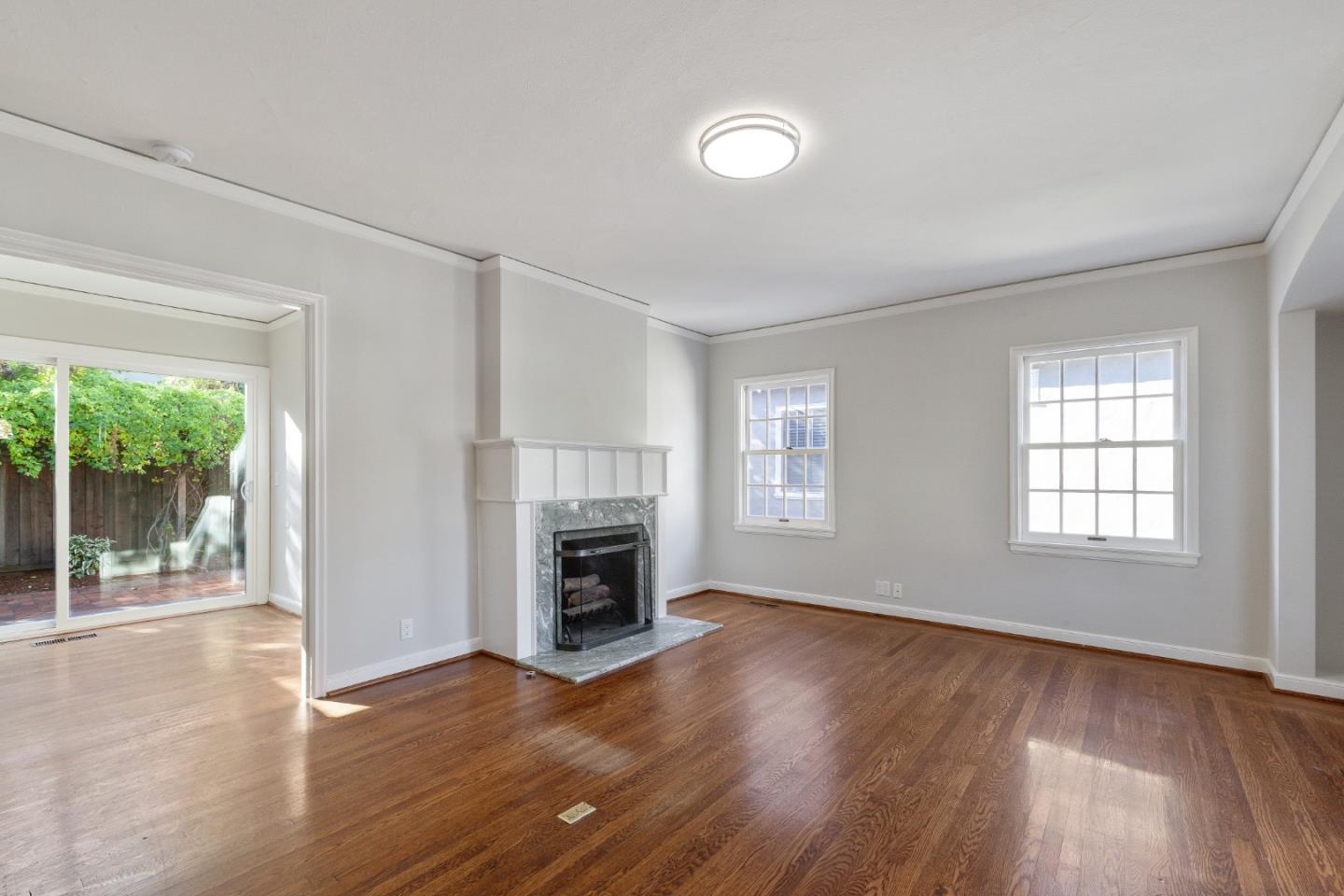 414 Williams Place San Mateo, CA 94401 - Photo 4 of 32 an empty room with wooden floor a fireplace and windows