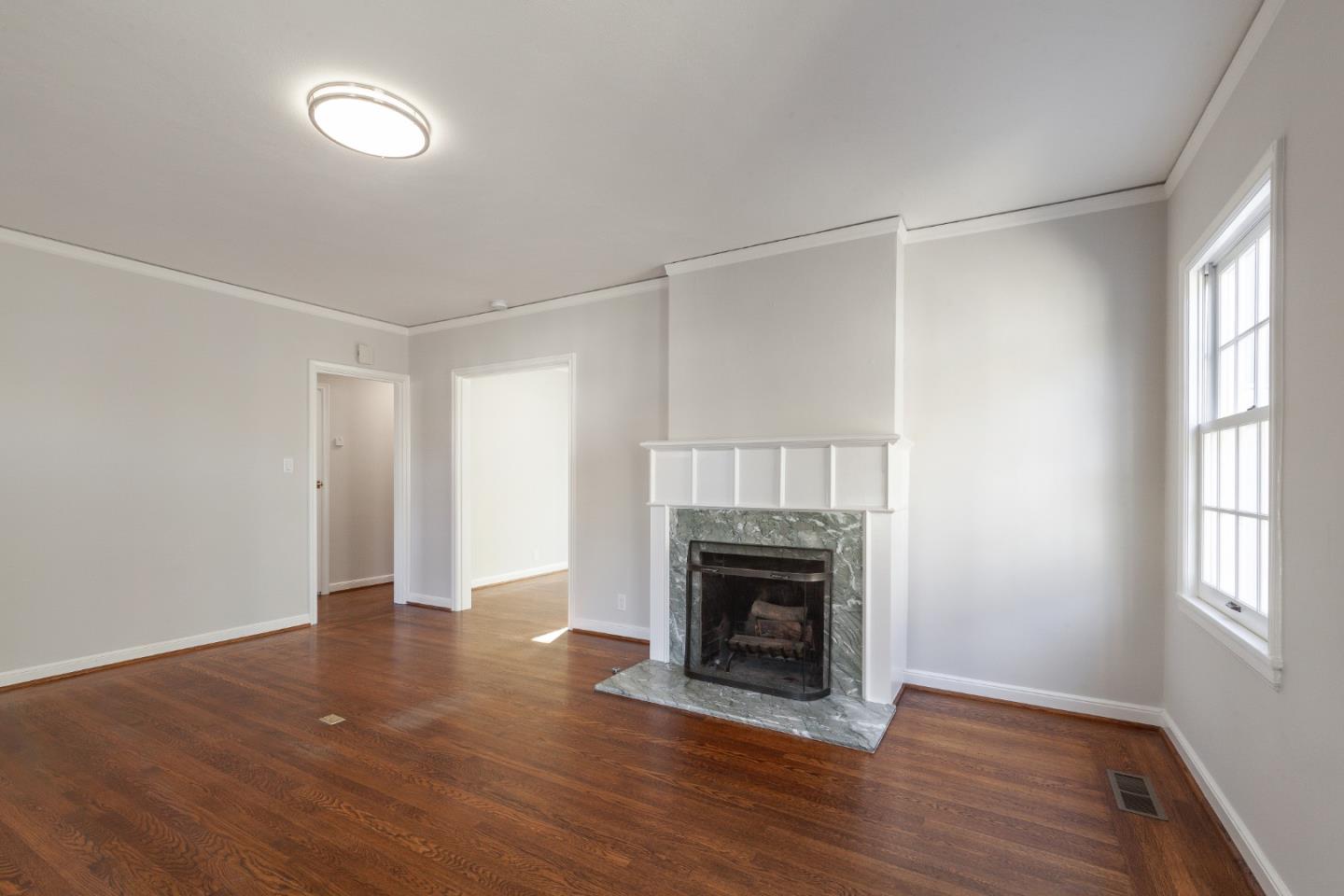 414 Williams Place San Mateo, CA 94401 - Photo 5 of 32 an empty room with wooden floor a fireplace and windows