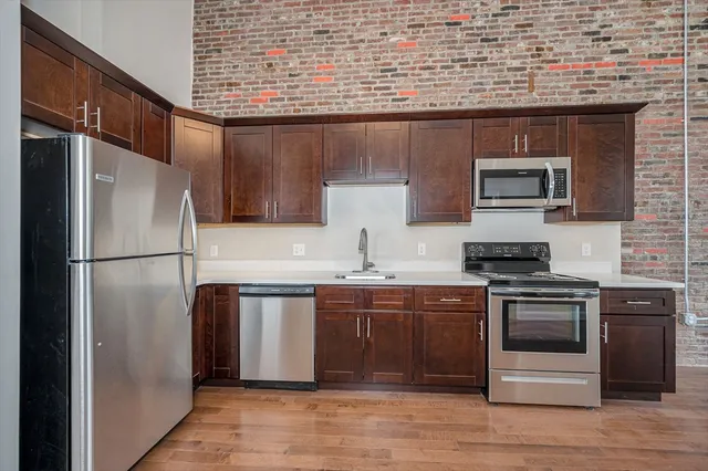 a kitchen with stainless steel appliances granite countertop a stove top oven a sink and a refrigerator