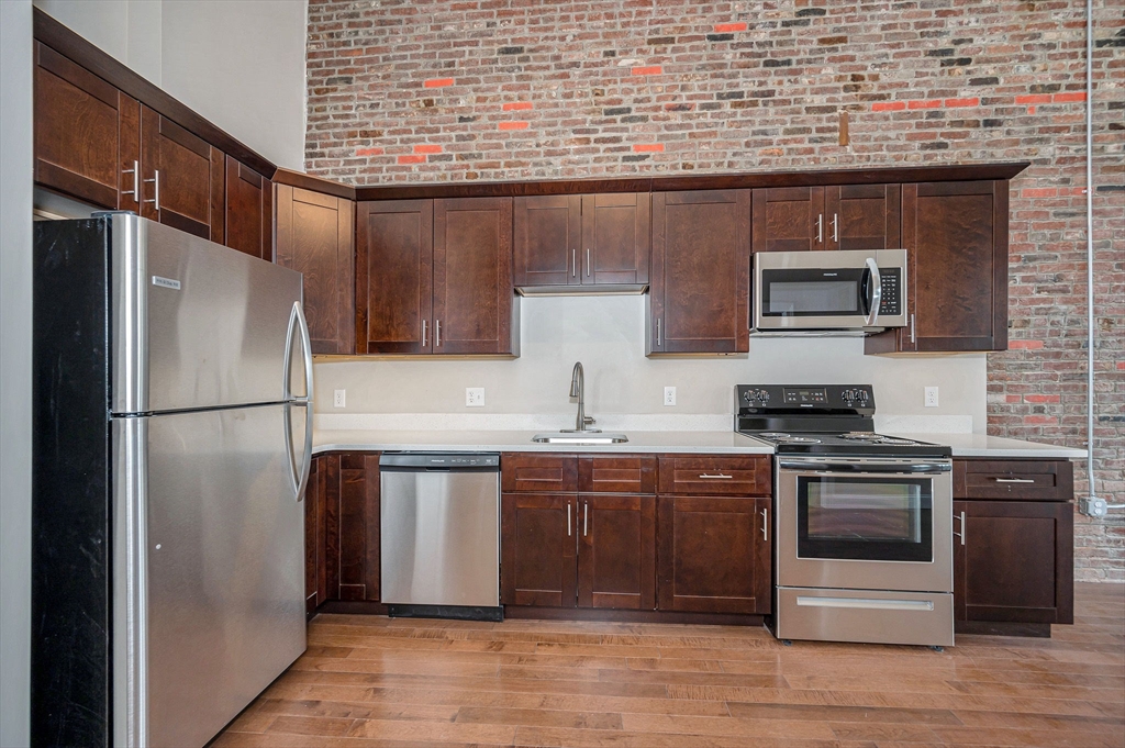 231 Central Street, Unit 203 Lowell, MA 01852 - Photo 6 of 15 a kitchen with stainless steel appliances granite countertop a stove top oven a sink and a refrigerator