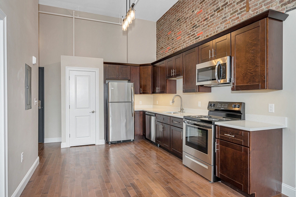 231 Central Street, Unit 203 Lowell, MA 01852 - Photo 8 of 15 a kitchen with stainless steel appliances granite countertop a refrigerator a stove a sink dishwasher and a microwave oven with cabinets