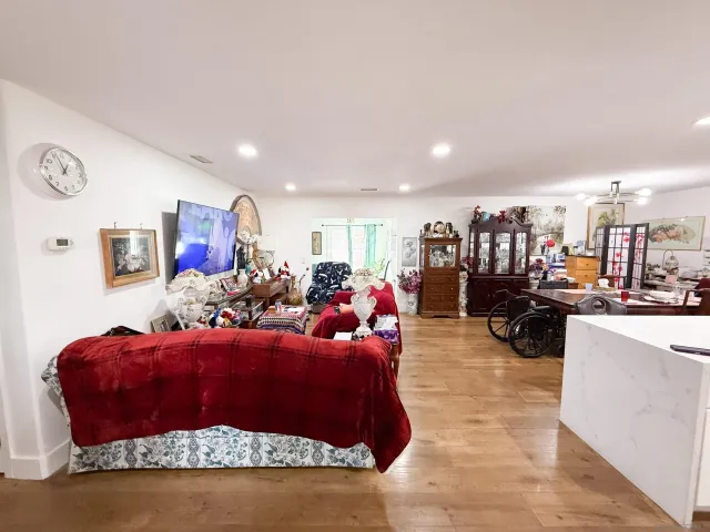 a living room with furniture hard wood floor and a kitchen counter top