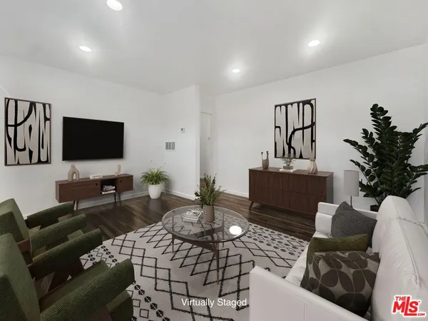 a living room with furniture a flat screen tv and a potted plant