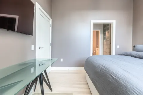 a bedroom with a bed and a flat tv screen on dresser