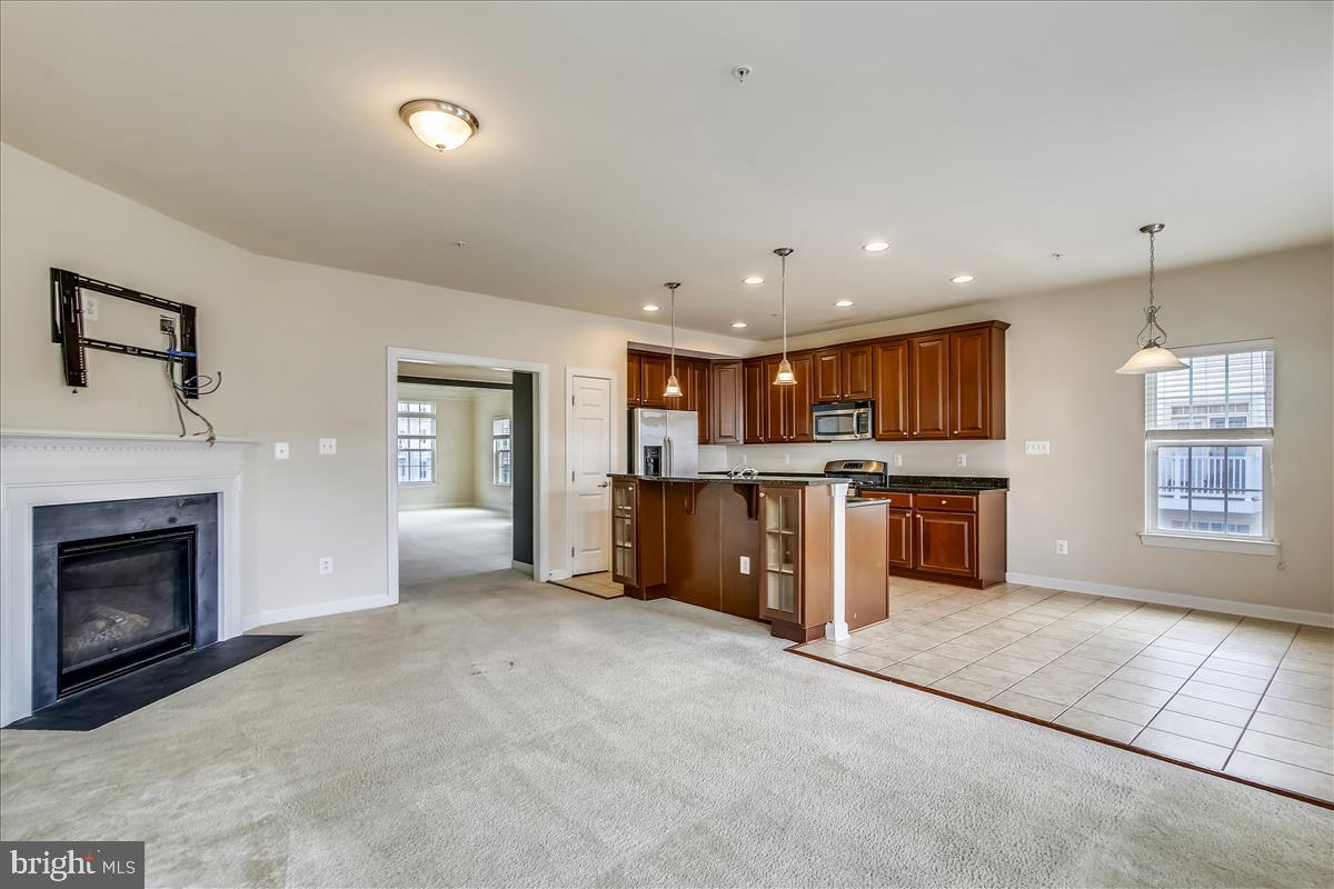 3602 Spring Hollow Lane Frederick, MD 21704 - Photo 10 of 25 a open kitchen with kitchen island a sink wooden floor and a fireplace