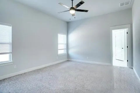an empty room with windows and fan