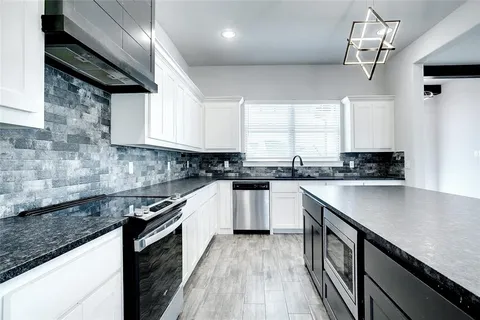 a kitchen with stainless steel appliances granite countertop a sink a stove and cabinets