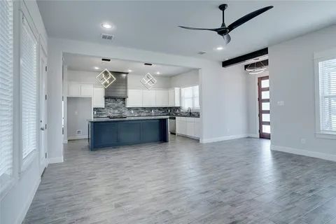 a large kitchen with stainless steel appliances granite countertop a refrigerator a stove and a wooden floors