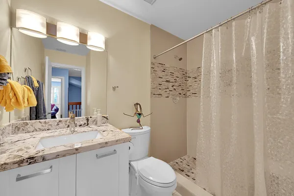 a bathroom with a granite countertop sink a toilet and shower