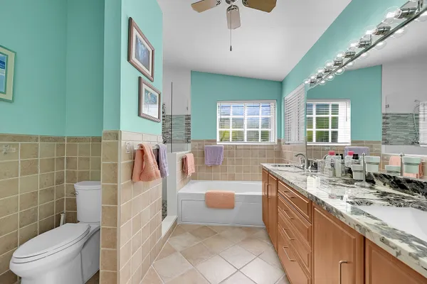 a bathroom with a granite countertop double vanity sink a mirror and a toilet