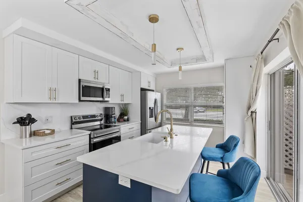 a kitchen with stainless steel appliances kitchen island granite countertop a table chairs in it and wooden floors