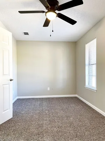 an empty room with a ceiling fan and window