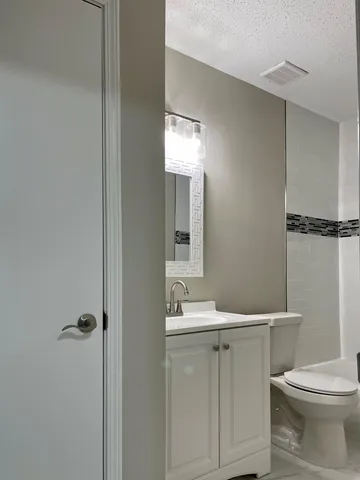 a bathroom with a toilet sink vanity and mirror