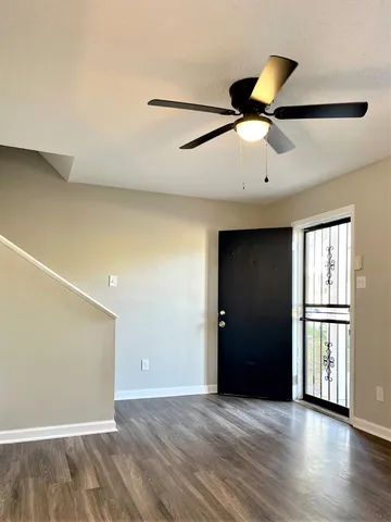 an empty room with wooden floor cabinet and windows