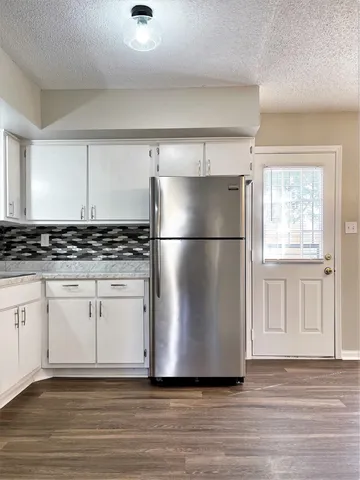 a kitchen with granite countertop a refrigerator and a stove top oven
