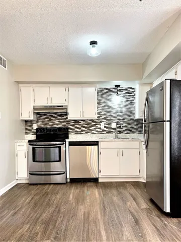 a kitchen with granite countertop white cabinets and stainless steel appliances