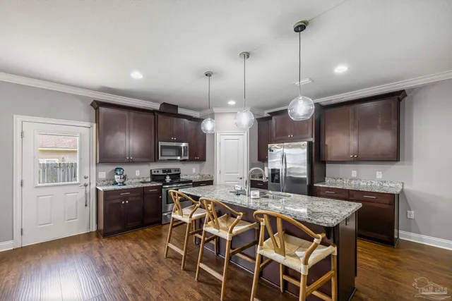 a kitchen with granite countertop a stove a sink a dining table and chairs