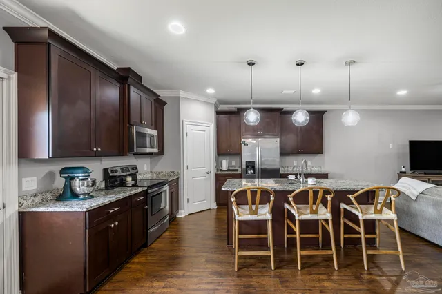 a kitchen with stainless steel appliances granite countertop wooden cabinets a dining table and chairs