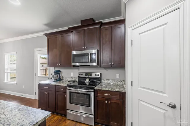 a kitchen with stainless steel appliances granite countertop a stove a sink and a microwave