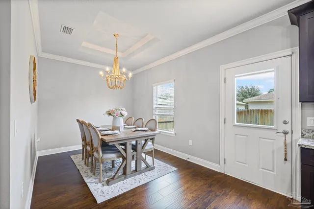 a view of a dining room with furniture a chandelier and wooden floor
