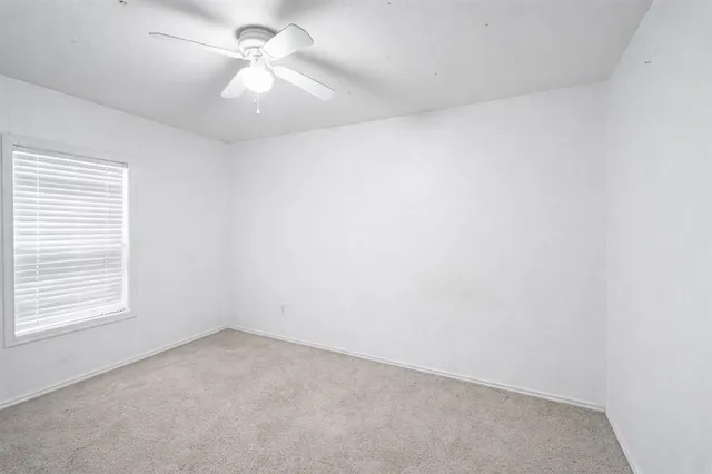 an empty room with a window and a ceiling fan