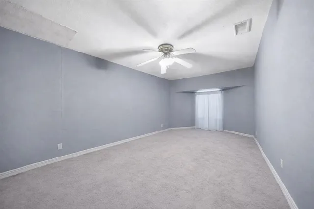 an empty room with a chandelier fan and windows