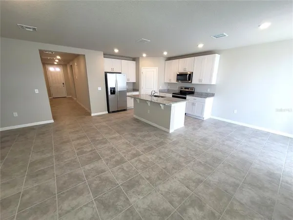 a view of kitchen with stainless steel appliances granite countertop a stove a sink and a refrigerator