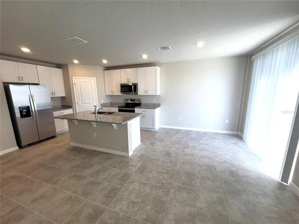 a large kitchen with stainless steel appliances granite countertop a stove a sink dishwasher and a refrigerator
