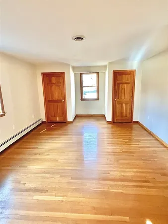 a view of an empty room with wooden floor and a window