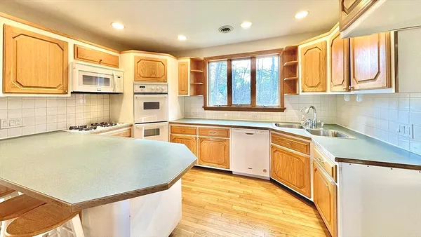 a kitchen with stainless steel appliances granite countertop a stove a sink dishwasher and a refrigerator with wooden floor