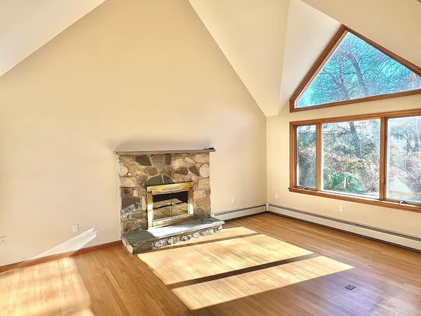 an empty room with wooden floor a ceiling fan and windows