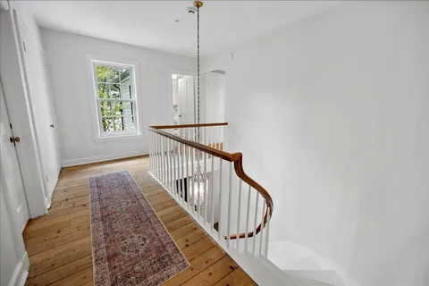 a view of hallway with window and wooden floor
