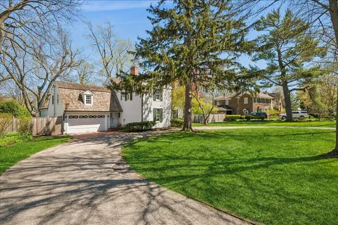 a view of a house with a big yard and large trees