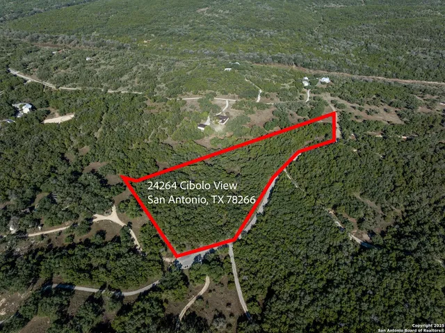 an aerial view of residential house with outdoor space and trees all around