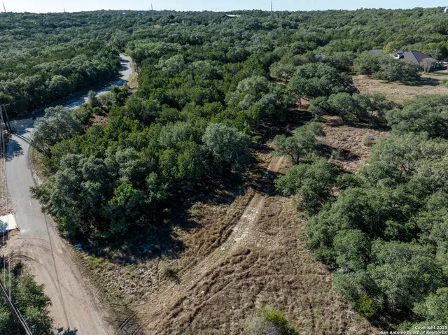 an aerial view of residential house with outdoor space and trees all around