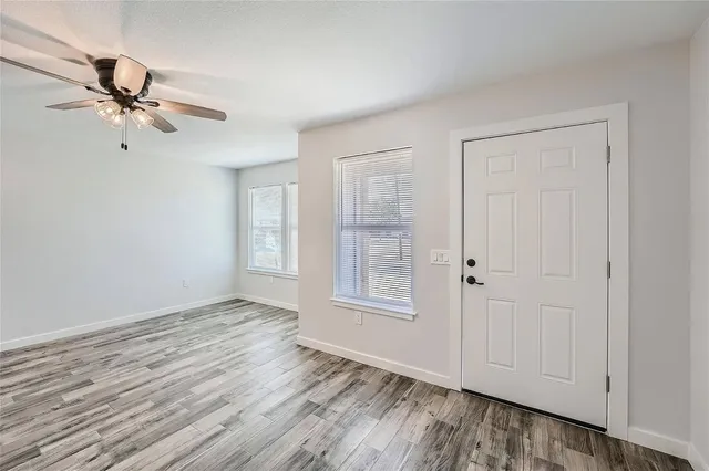a view of empty room with wooden floor and fan
