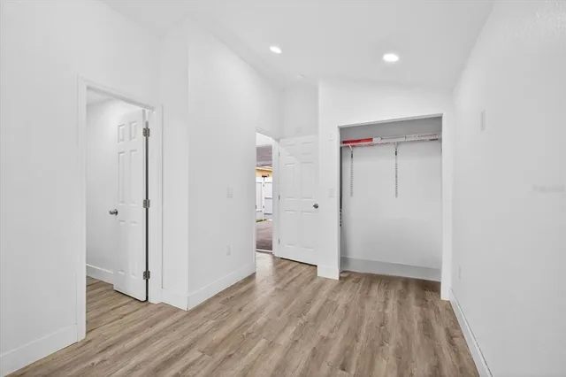 an empty room with wooden floor and fan