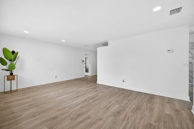 a view of an empty room with a window and wooden floor
