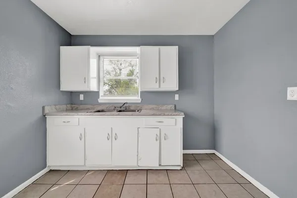 a kitchen with granite countertop white cabinets white appliances a sink and a window